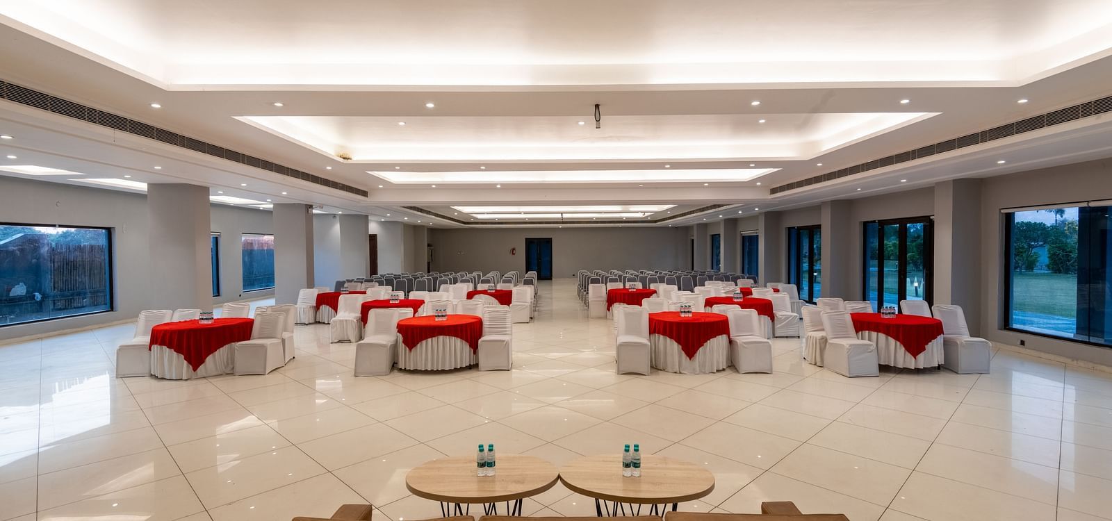 Tables with neatly decorated tablecloths, a plush sofa, and two round tables set in front at DLS Forest Vines Resort.